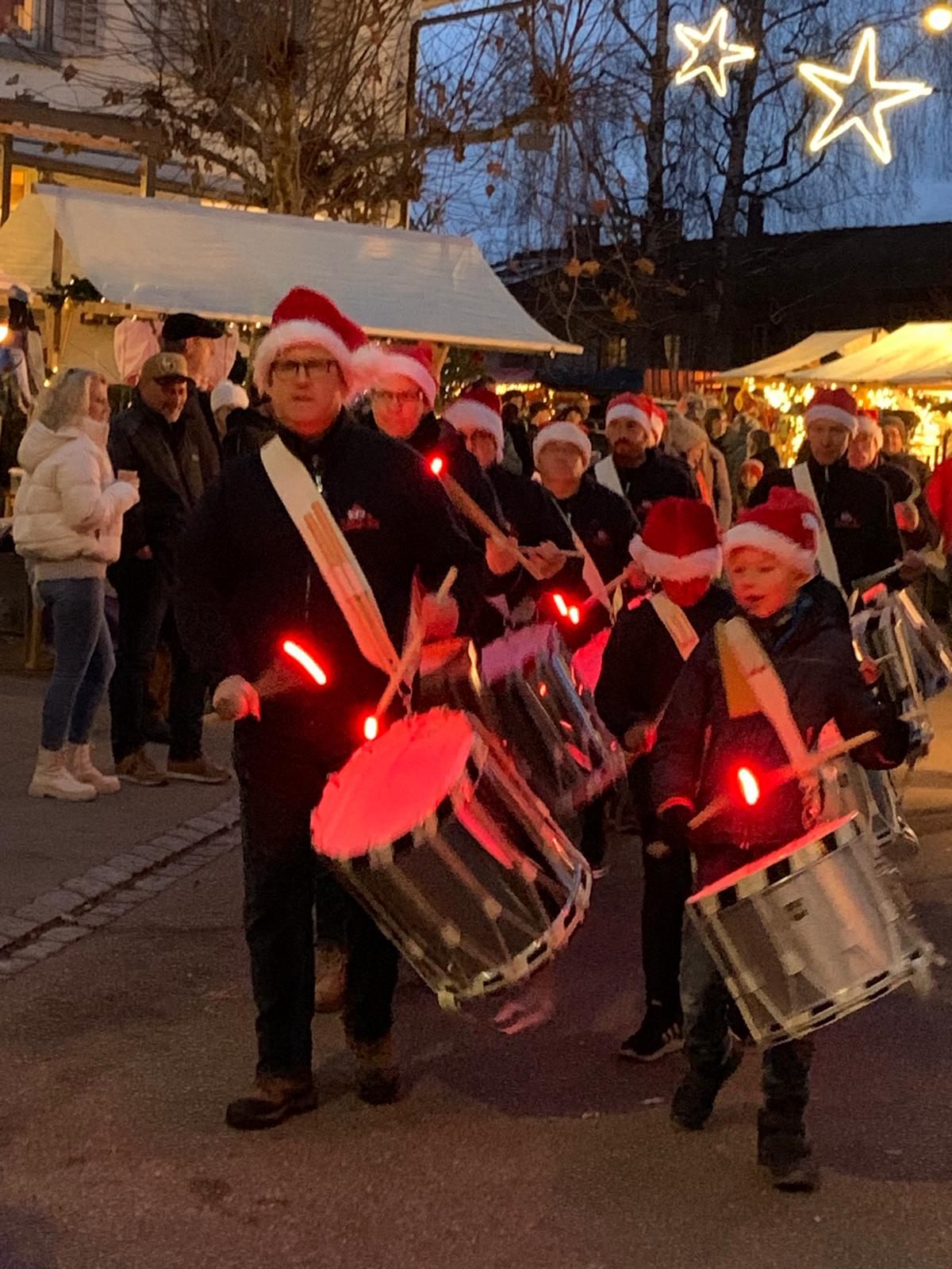 Trommler mit Samichlaus-Mützen im Umzug, Sternlichter über dem Markt